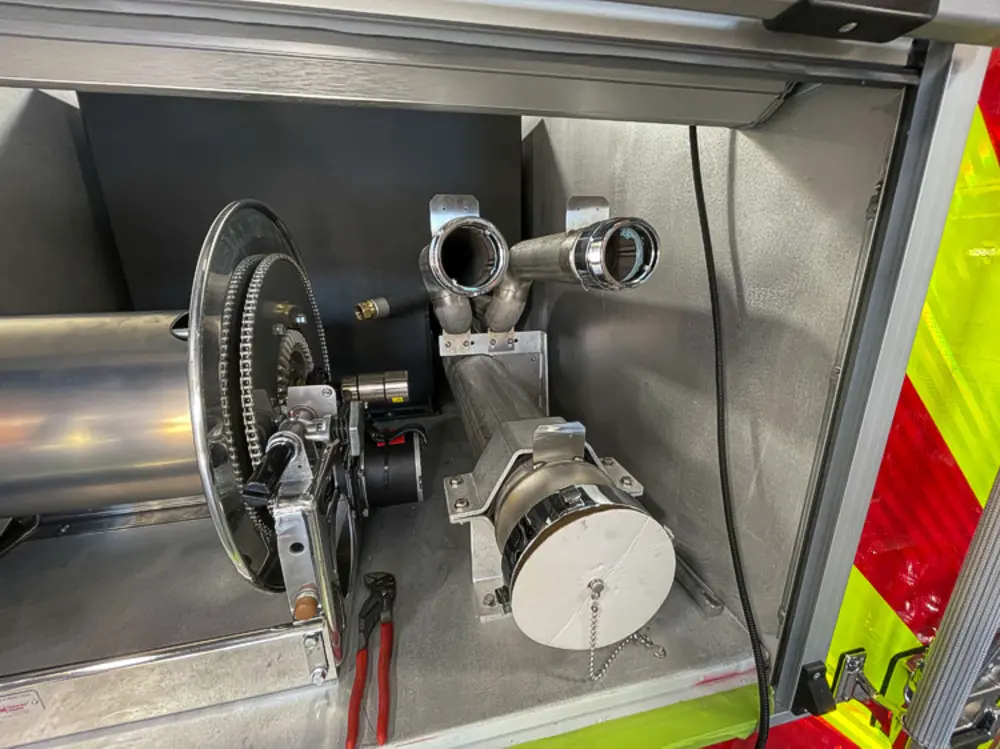 Exterior view of small fire truck showing cab, body compartments, and wheel/tire area.